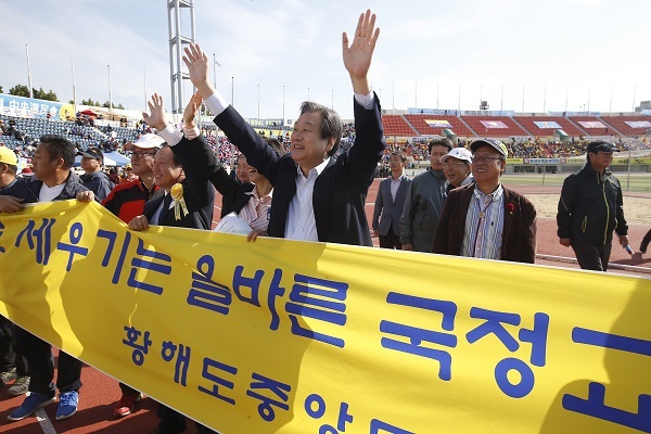 Ruling Saenuri Party chairman Rep. Kim Moo-sung (center) walk along with other participants with a banner promoting state-authored textbook at a presidential sports event gathering those originating from North Korean provinces and North Korean defectors at Mokdong Stadium in western Seoul, Sunday. Yonhap