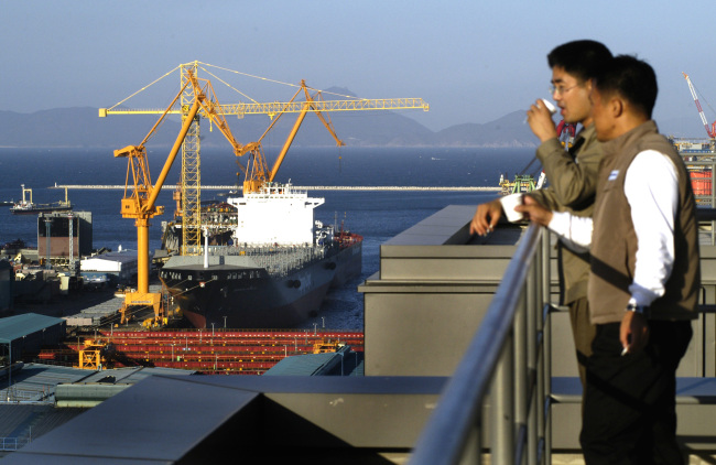 Daewoo Shipbuilding & Marine Engineering employees take a break on a building's rooftop overlooking the shipyards on Geoje Island in South Korea. (Bloomberg)