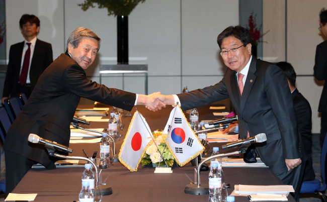 FOR CLOSE TRADE PARTNERSHIP -- Korea’s Minister of Trade, Industry and Energy Yoon Sang-jick (right) shakes hands with Japanese Minister of Economy Motoo Hayashi at their regular meeting for close trade ties at a hotel in Seoul on Friday. (Yonhap)