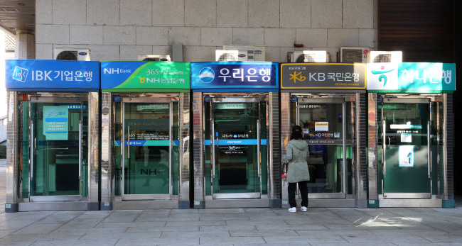 A citizen passes by a row of ATM machines in Seoul on Thursday, a day before account switching systems took off. (Yonhap)