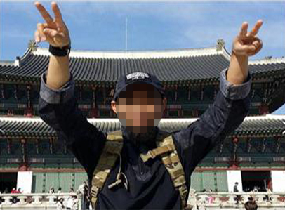 In this photo released by police, an Indonesian migrant worker suspected of supporting the international terrorist group the Nusra Front poses wearing a hat with the group’s logo in front of Gyeongbokgung Palace in October. (National Police Agency)