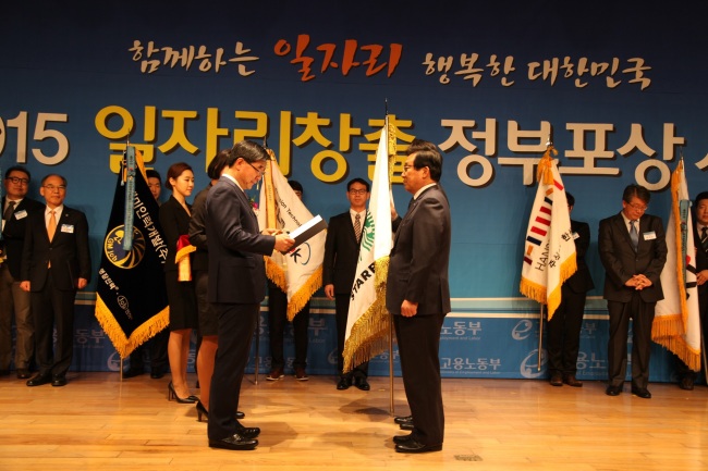 AWARD FOR JOB CREATION -- Starbucks Coffee Korea CEO Lee Seock-koo (right) receives a government order of merit from Employment and Labor Minister Lee Ki-kweon for the company’s contribution to job creation on Tuesday in Seoul. The coffee shop operator hires an average of 10 staff members for every new store, all with a regular work contract instead of part-time. Starbucks Coffee Korea