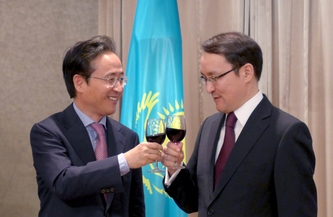 Shin Bong-kil (left), president of the Institute of Foreign Affairs and National Security, and Kazakh Ambassador Dulat Bakishev clink their glasses at a reception marking Kazakhstan’s National Day on Tuesday in Seoul. Joel Lee/The Korea Herald