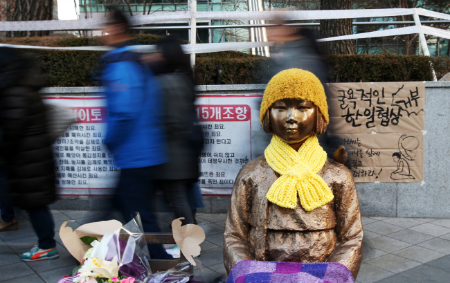 Pedestrians walk past a statue symbolizing Korean victims of Japan`s wartime sex slavery set up in front of the Japanese Embassy in Seoul. Tokyo has demanded to remove the statue as part of Monday`s South Korea-Japan settlement over the 