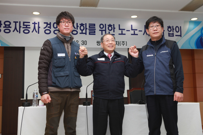 Ssangyong Motor CEO Choi Johng-sik (center), labor union leader Hong Bong-seok (right) and head of the Ssangyong Motor chapter of  the Korea Metal Workers’ Union Kim Deuk-jung pose after striking a final settlement on the six-year labor dispute on Wednesday. (Ssangyong Motor)