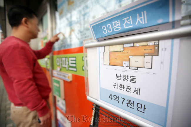 A citizen examines apartment rent price tags posted outside a real estate agency in Seoul on Sunday. (Yonhap)