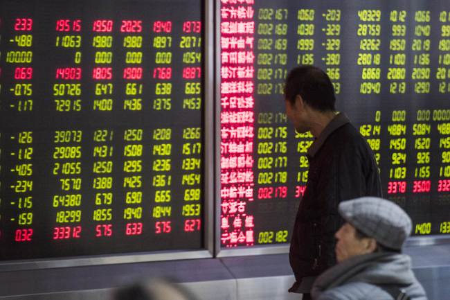 An investor looks at screens showing stock market movements at a securities company in Beijing on Jan. 5. (AFP-Yonhap)