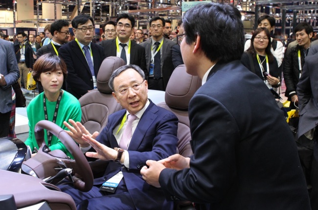 KT AIMS TO BOLSTER GLOBAL PARTNERSHIP -- KT chairman Hwang Chang-gyu (center) paid a visit to the exhibit booth of Kia Motors at the International CES trade show in Las Vegas on Wednesday. He also had meetings with top executives of global tech firms including Samsung Electronics, LG Electronics and Qualcomm to discuss the latest trends of the tech sector and future partnerships. (KT)