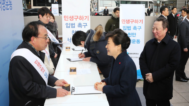 PUBLIC PETITION TO URGE BILL PASSAGE -- President Park Geun-hye (center) on Monday visits a campaign site organized by the Korea Chamber of Commerce and Industry led by chairman Park Yong-maan (right) to urge legislators to pass a set of bills on labor reform and economic recovery at the KCCI building in central Seoul. The campaign seeks to collect and submit the signatures of 10 million citizens to the National Assembly, with the aim of putting pressure on the partisan deadlock that has delayed passage of the bills for several months. KCCI