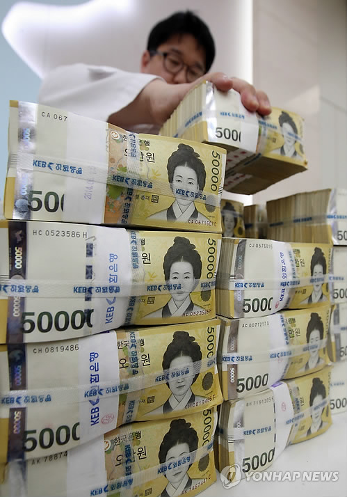                South Korea’s highest denomination 50,000 won bills are being stacked at               a local bank. (Yonhap)