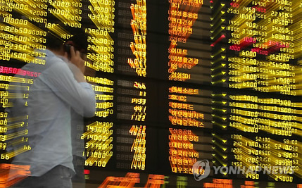 An investor walks past an electronic board displaying South Korean share prices. (Yonhap)