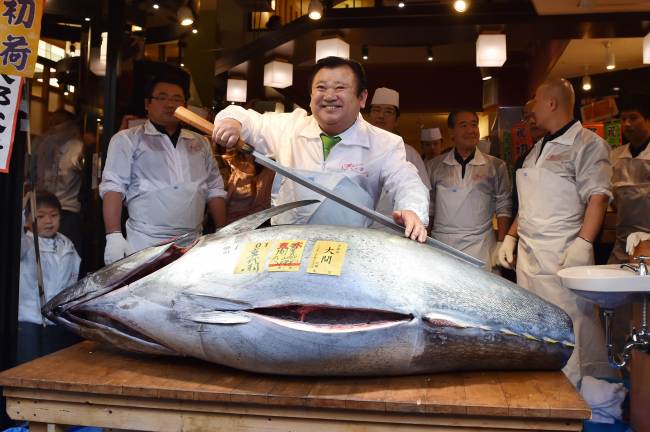 President of sushi restaurant chain Sushi-Zanmai, Kiyoshi Kimura (center) holds a long fish knife as he poses with a 200-kilogram bluefin tuna at his main restaurant near Tokyo‘s Tsukiji fish market on Jan. 5. (AFP-Yonhap)