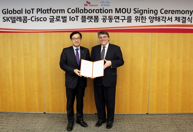 SK Telecom chief technology officer Choi Jin-sung (left) and Cisco’s global head of service provider practice Scott Puopolo pose after signing a memorandum of understanding at the telecom carrier’s Seoul headquarters on Friday. SK Telecom