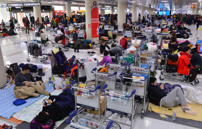 Travelers wait on the floor at Jeju International Airport`s passenger terminal early Monday. (Yonhap)
