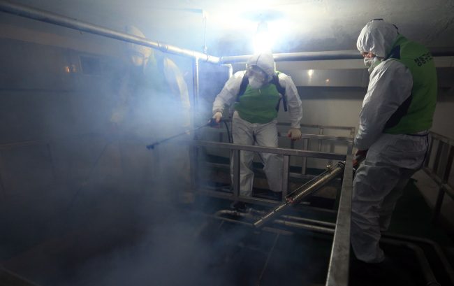 Health officials spray mosquito repellent as part of preventive measures against the Zika virus at the underground septic tank of an apartment in Oksu-dong, Seoul, Thursday. (Yonhap)