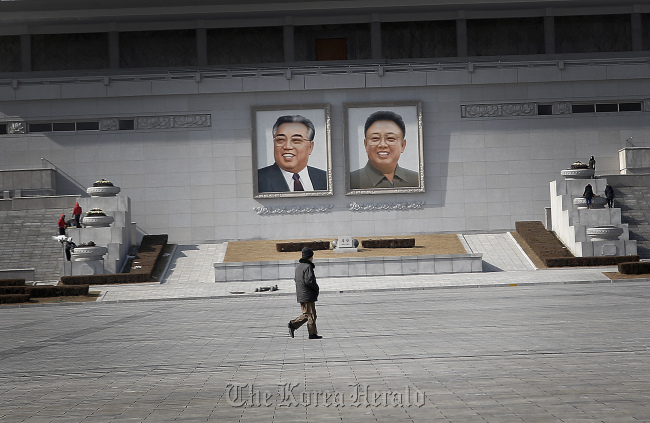 A man walks past the portraits of the late North Korean leaders Kim Il-sung and Kim Jong-il, at the Kim Il-sung Square on Sunday in Pyongyang. (AP-Yonhap)