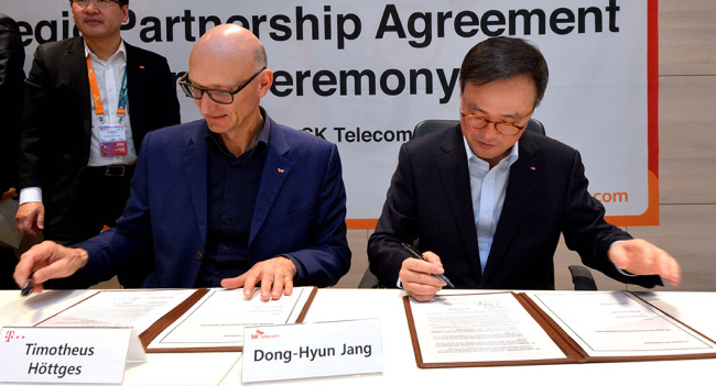 SK Telecom CEO Jang Dong-hyun (right) and Deutsche Telekom CEO Timotheus Hoettges take part in a signing ceremony for a partnership deal between the two telecom firms in Barcelona on Monday. (SKT)