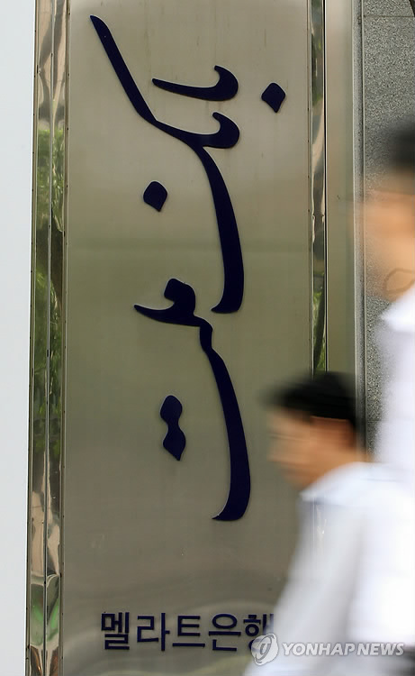 A citizen walks past the signboard of Iran’s Mellat Bank in Seoul. (Yonhap)