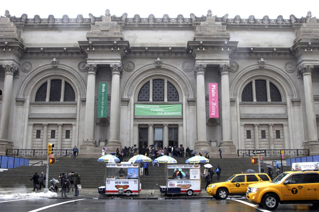 Patrons stand in the rain by the front doors of the Metropolitan Museum of Art in New York in March 2013. (AP Photo)