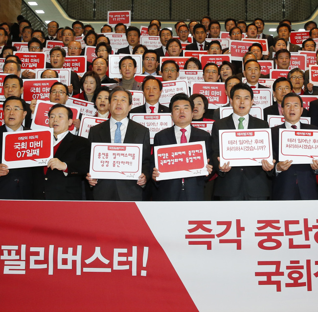 Saenuri Party lawmakers hold up placards to protest aganist the opposition-led filibuster at the National Assembly. (Yonhap)