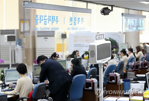 Employees serve customers at a local bank. (Yonhap)