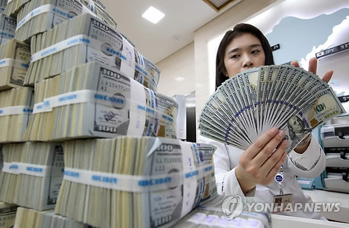 An employee count outs dollars at a local bank. (Yonhap)