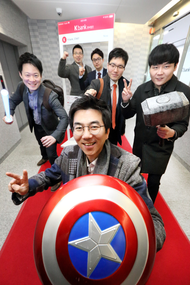 K-BANK’S HEAD OFFICE -- Employees of the K-Bank online-only bank, which will be incorporated in the coming months, pose with items featured in the Avengers movie series at an event to celebrate the bank’s first day at the office at The K Twin Tower in Gwanghwamun, Seoul, Monday. (KT)