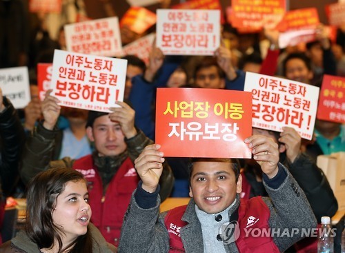 Participants hold up cards with slogans that promote better protection of the rights of immigrant workers, during an event marking International Migrants Day in Seoul in December, 2015. (Yonhap)