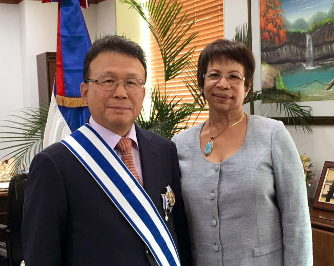 Caption: Dominican Republic Ambassador Grecia Fiordalicia Pichardo (right) awards Park Dong-sil, former Korean ambassador to the Caribbean nation, with a distinguished medal from her government at the embassy on Wednesday. (Dominican Embassy)