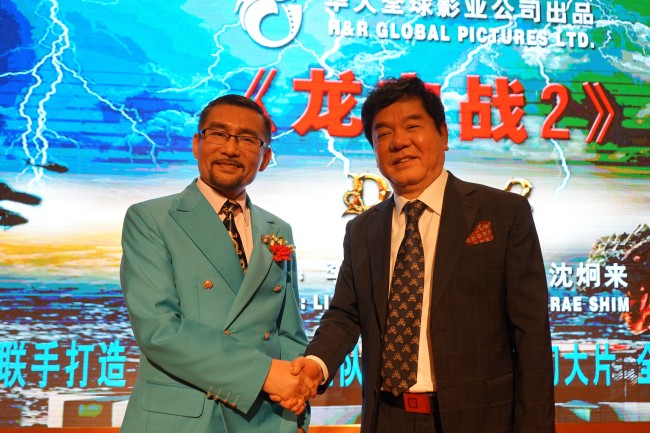 Comedian-turned-filmmaker Shim Hyung-rae (right) shakes hands with Li Xin of H&R Global Pictures Ltd., the movie production and distribution arm of the state-run Chinese Culture Group Co., which has invested 500 million yuan ($77.3 million) in Shim’s new movie, “D-War II: Mysteries of the Dragon.” (Yonhap)