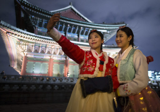 Women wearing hanbok take selfies during the Gyeongbokgung Palace moonlight tour on March 2. (Yonhap)