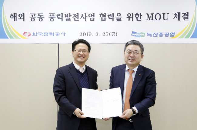 Yang Won-chang (left), Doosan Heavy Industries & Construction’s new business development division head, and Lim Cheong-won from the Korea Electric Power Corporation pose after signing a memorandum of understanding, forming a partnership on Friday for wind-power plant projects overseas. (Doosan Heavy Industries & Construction)