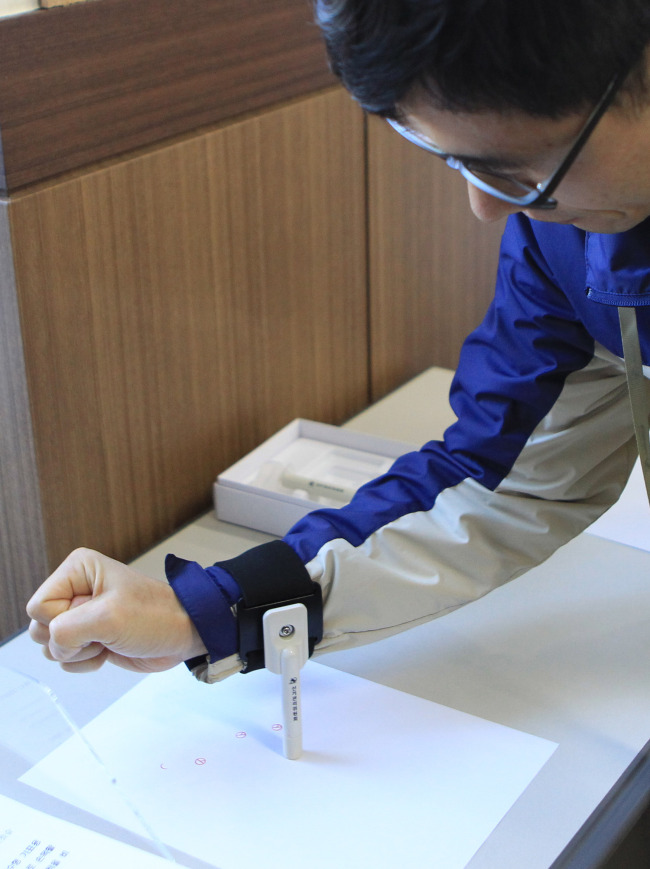 An official demonstrates how to use equipment designed to help people who have difficulties using their hands to cast ballots at the National Election Commission’s district office in Changwon on March 17. Yonhap