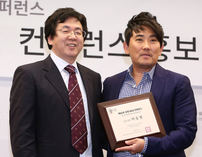 Singer Lee Seung-chul (right) holds a plaque commemorating his appointment as promotional ambassador for the 66th U.N. DPI/NGO Conference, next to the conference’s executive committee chairman Chang Soon-heung on Thursday at the Korea Press Center in Seoul. (Yonhap)