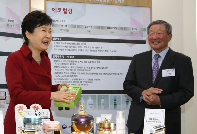 PRESIDENT’S VISIT TO INNOVATION CENTER -- President Park Geun-hye (left) and LG Group chairman Koo Bon-moo look at products made by venture companies based at the Center for Creative Economy and Innovation in North Chungcheong Province, a start-up incubation center run by the conglomerate, on Friday. (Yonhap)