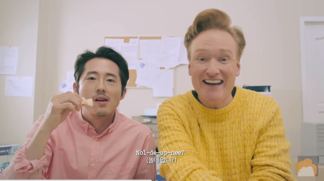 Korean-American singer and actor Steven Yeun (left) and American comedian and talk show host Conan O’Brien star in JYP’s “Fire” music video (JYP Entertainment)