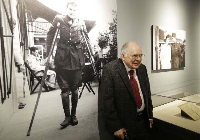 Patrick Hemingway, son of Ernest Hemingway, stands near a 1918 photograph of his father that shows him on crutches in Italy while recovering from war wounds during World War I (left) as he visits the exhibit, “Ernest Hemingway: Between Two Wars” at the John F. Kennedy Presidential Library and Museum, in Boston on Tuesday. (AP-Yonhap)