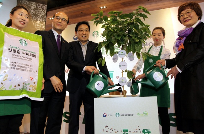 COFFEE RECYCLING - Vice Environment Minister Jeong Yeon-man (second from left) and Starbucks Coffee Korea CEO Lee Seock-koo (third from left) water a plant Thursday after signing an agreement to turn used coffee grounds collected across Starbucks outlets nationwide into eco-friendly compost, animal feed and other repurposed substances for local usage. This year, the two plan to collect roughly 3,500 tons of used coffee grounds for recycling purposes. (Starbucks Coffee Korea)