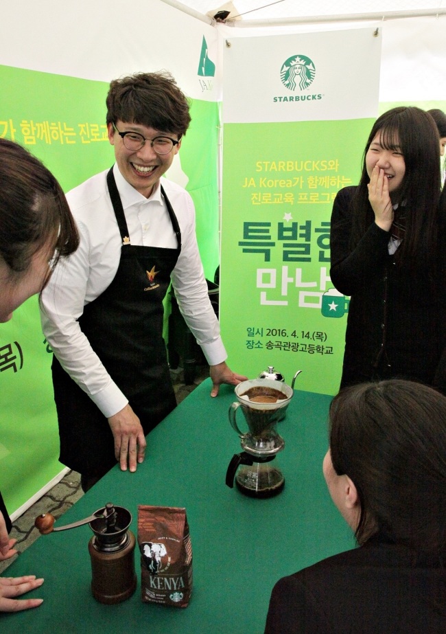 STARBUCKS SOCIAL CONTRIBUTION -- A barista from Starbucks Coffee Korea (left) offers career consulting and training to students from Songgok Tourism High School in Seoul on Friday as part of a career development program led by Starbucks in partnership with Junior Achievement, a U.S.-based nonprofit youth organization. Starbucks plans to hold similar programs in high schools within and outside of Seoul until November as part of joint social contribution efforts. (Starbucks Coffee Korea)