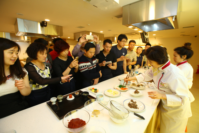A group of Chinese tourists learn to make bibimbap during a Korean cuisine cooking tutorial class last week at K-Style Hub in central Seoul. (Korea Tourism Organization)