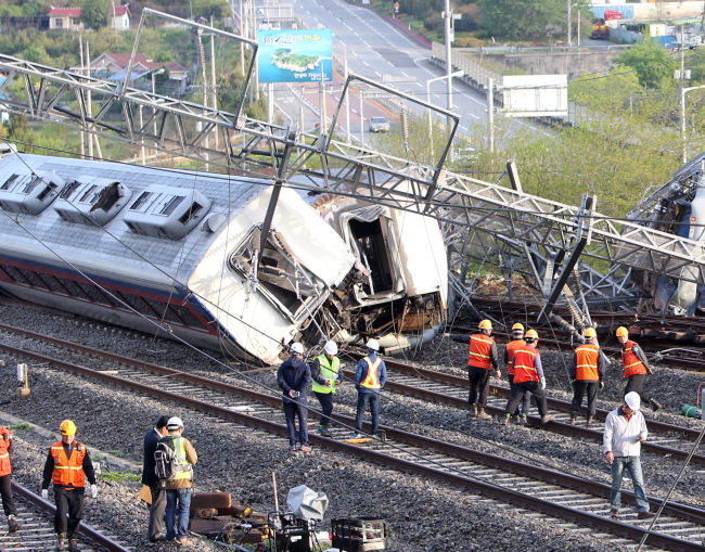 Officials of state-run railway operator KORAIL perform rescues and restorations Friday at the scene of a passenger train derailment around Yulchon Station in Yeosu, South Jeolla Province. The accident left one dead and eight injured. (Yonhap)