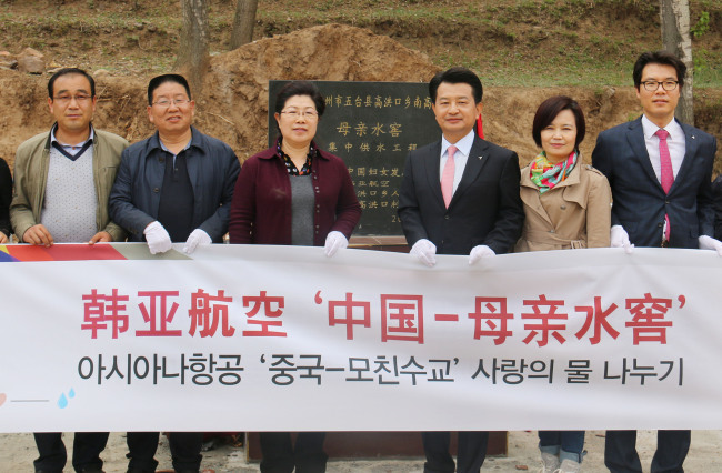 WATER FOR CHINA -- Ahn Byeong-seog (third from right), president of Asiana Airlines’ China Regional Headquarters, Ren Jinyang (fourth from right), director of the Women’s Federation of Shanxi province, and other participants pose in Nangaohongkou, Shanxi province, on Tuesday. Asiana Airlines donated five water cellars, pipelines, and drinking water fountains for the arid village through the Chinese Water Cellar for Mothers Project. (Asiana Airlines)