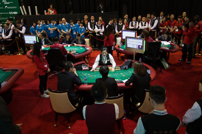 Dealers compete at baccarat tables during the All Asia Dealers' Championship at the Global Gaming Expo (G2E) in Macau, China, May 19, 2015. (Bloomberg)