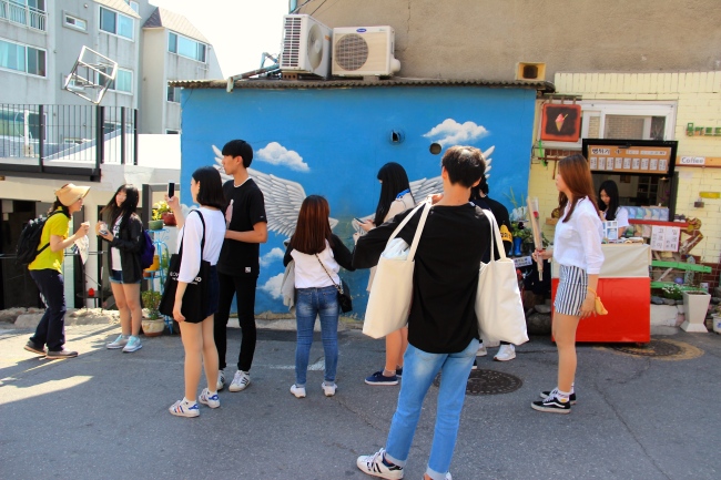 Tourists wait to take pictures at the popular Ihwa Mural Village. (Julie Jackson/The Korea Herald)