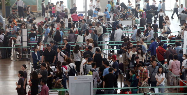 South Koreans headed overseas line up at the Incheon International Aiport in this file photo from June. The Investor