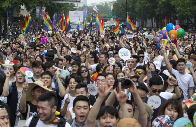 Participants march through central Seoul at the Pride Parade, waving rainbow-colored fans and flags, Saturday. (Yonhap)