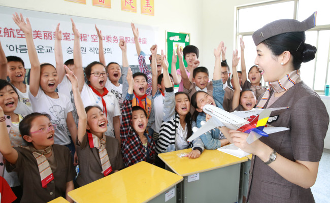 An Asiana Airline cabin crew member interacts with students at Xintan Elementary School in Jiangsu province, China, Tuesday. Asiana Airlines donated eight computers, 400 desks and 1,000 books to the school as part of its 25th Beautiful Classroom partnership. The Beautiful Classroom project is Asiana Airlines’ global corporate social responsibility program, sponsoring schools in China since 2012. Pictured: (Asiana Airlines)