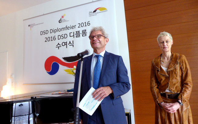 German Ambassador Rolf Mafael (left) addresses Korean high school students who completed their German language courses provided by the German government beside program coordinator Catrin Inis Beguhl at the embassy on Tuesday. (Joel Lee/The Korea Herald)