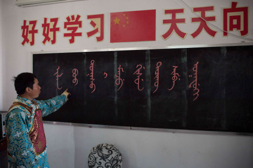 School teacher Shi Junguang in a classroom with a blackboard that reads, “Welcome to the Sanjiazi Manchu school,” and above the blackboard Chinese letters say, “Study hard and every day you will improve” at the Sanjiazi Manchu school in Sanjiazi village, Heilongjiang province, on May 4. (AFP-Yonhap)