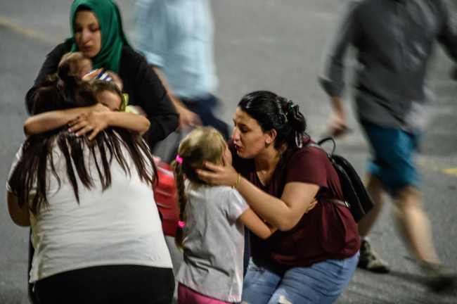 어린이들과 그들의 가족들이 공항을 떠나며 서로 껴안고 있다. (AFP-연합뉴스)